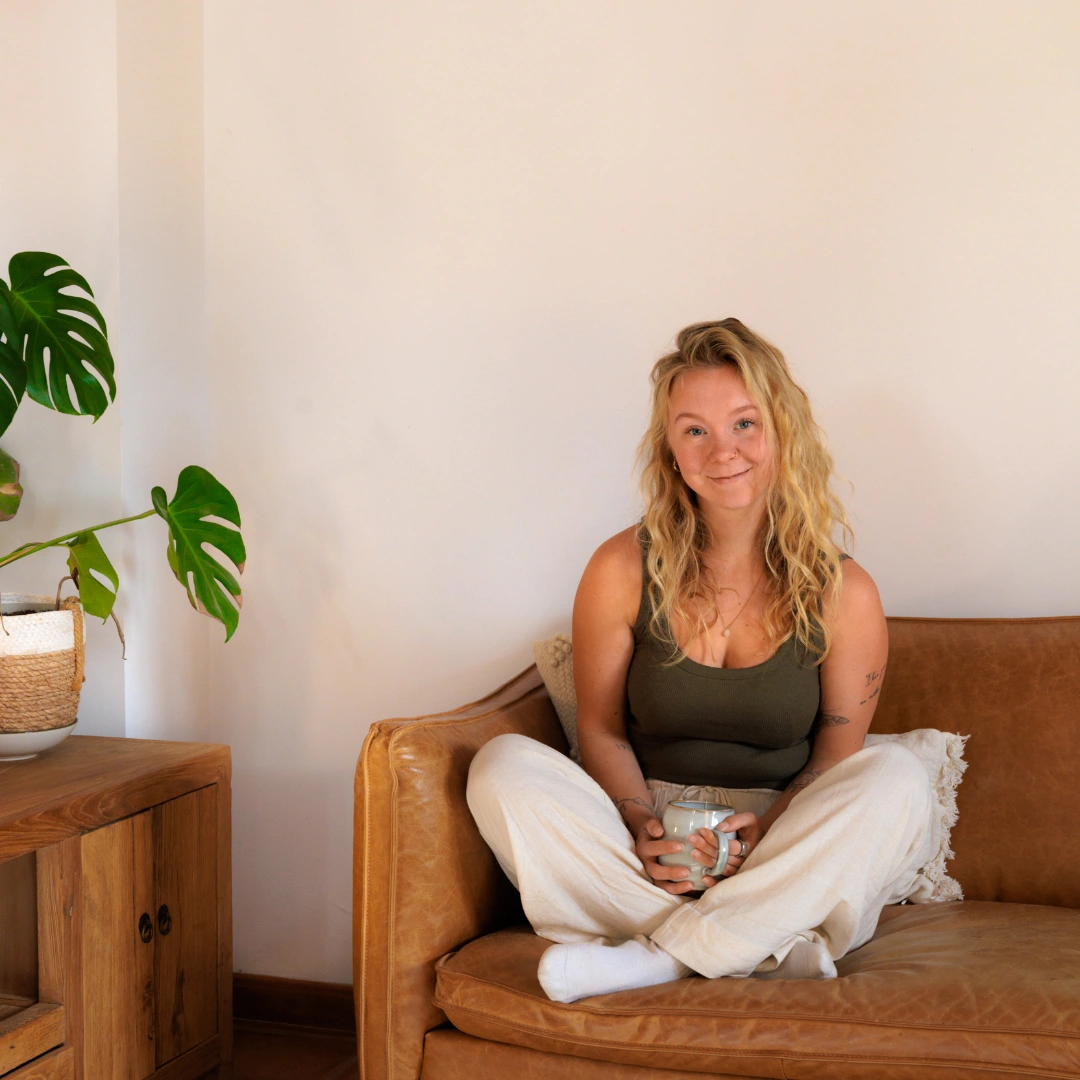 Jenice, hormoon- en voedingscoach, thuis op de bank met een kop thee